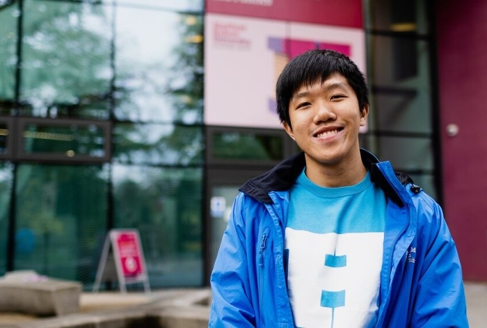 student stood smiling in front of University building